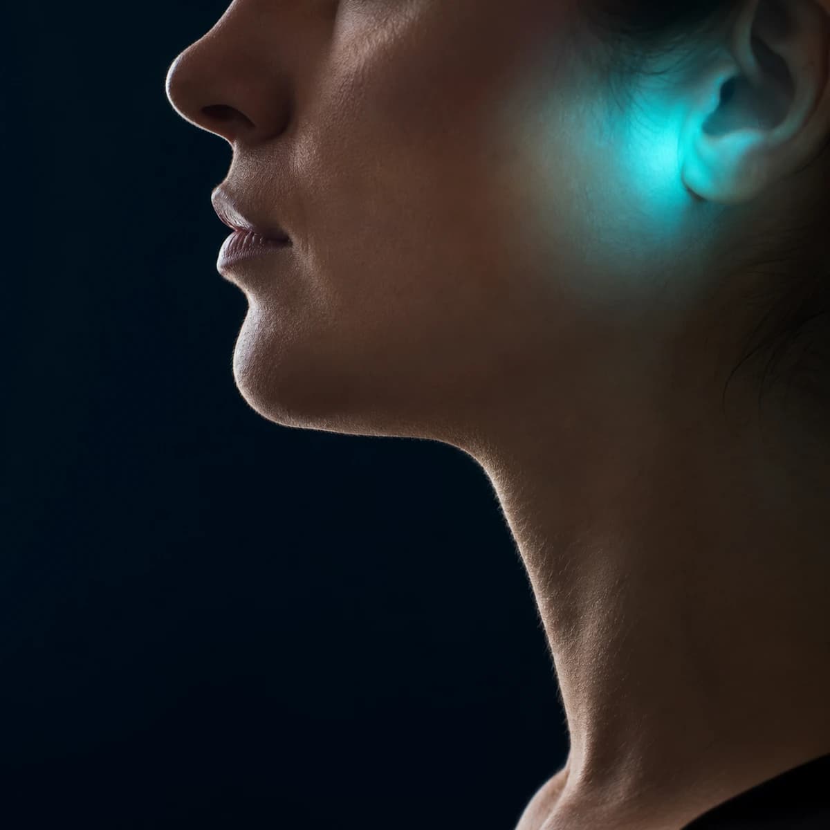 Perfil de uma mulher com a zona da articulação temporomandibular, à frente do ouvido, destacada em azul
